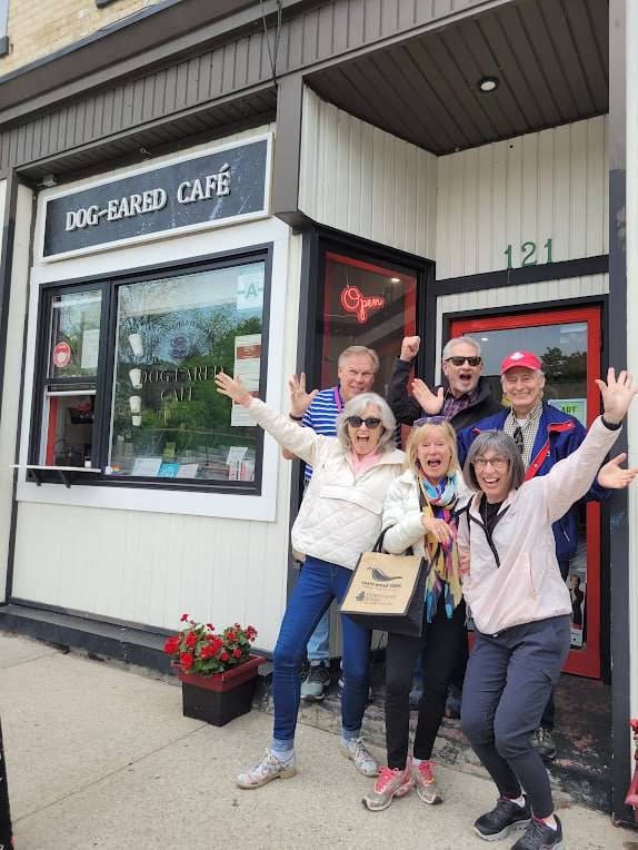 older people posing in front of a street entrance to a cafe