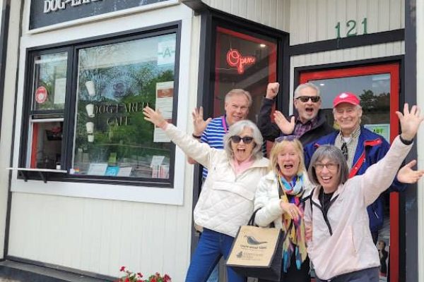 older people posing in front of a street entrance to a cafe
